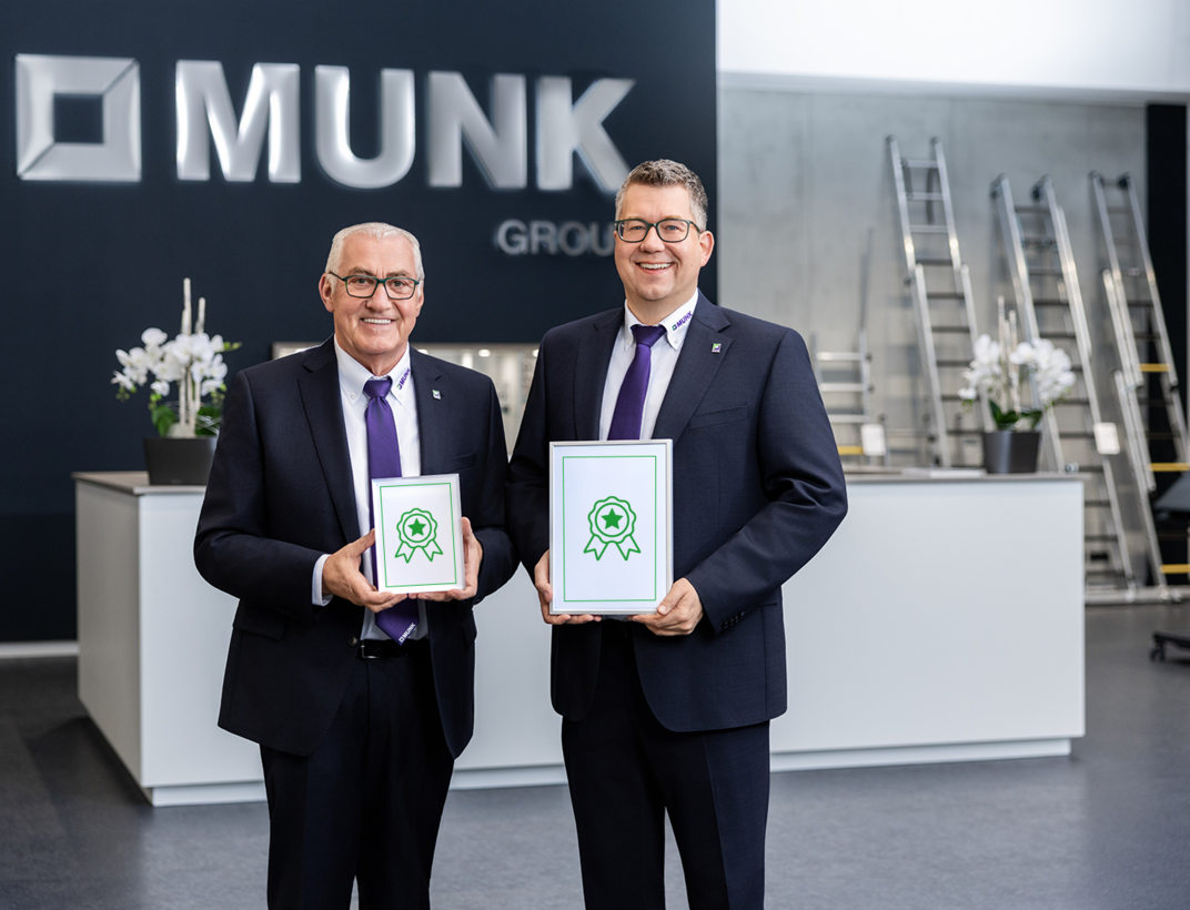 Ferdinand Munk et Alexander Werdich sourient en tenant deux certificats dans le centre clientèle de la MUNK Group. | © MUNK GmbH