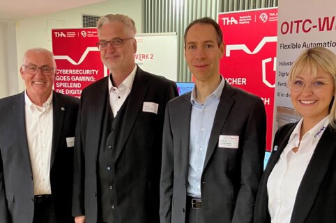 Herr Munk und Frau Linder der MUNK Group stehen vor den Roll-Ups des   „Tag der digitalisierten Produktion“ der Technischen Hochschule Augsburg.
