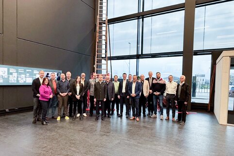 Einige Mitglieder des BVMW stehen im Halbkreis für ein Gruppenfoto in der Rettungstechnik Leipheim zusammen.