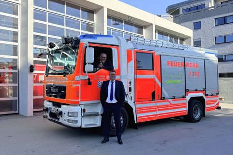 Ferdinand Munk und Alexander Werdich, Geschäftsführer der MUNK Group, stehen vor einem Feuerwehrfahrzeug und lächeln in die Kamera.