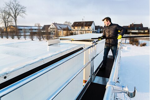 Mit dem Eisschieber der Munk Günzburger Steigtechnik, der als Zubehör erhältlich ist, lassen sich Schnee und Eis einfach und schnell von den Fahrzeugen entfernen. | © MUNK GmbH