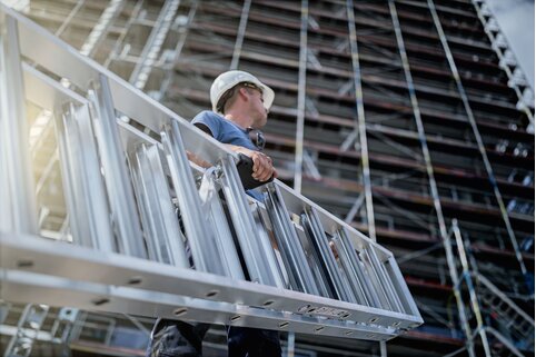 Les échelles à marches avec la zone de préhension ergonomique "ergo-pad" peuvent toujours être portées de manière ergonomique au point d'appui optimal. | © MUNK GmbH