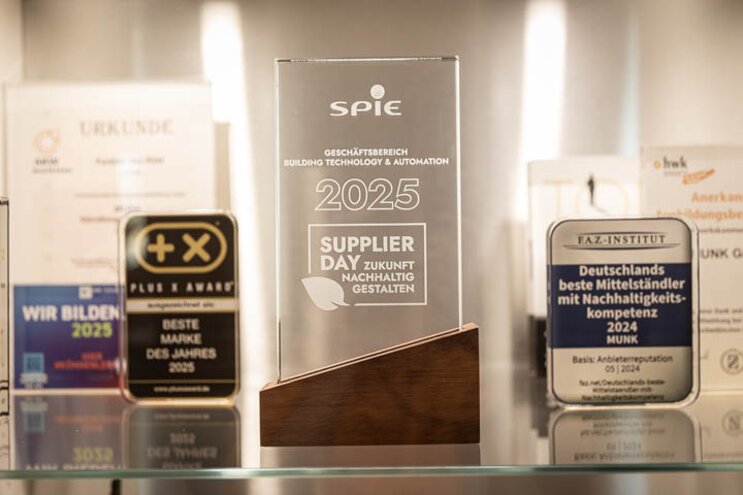 Gläserner Award von SPIE für MUNK Group vor der Vitrine im Kundenzentrum der Munk Group. | © MUNK GmbH